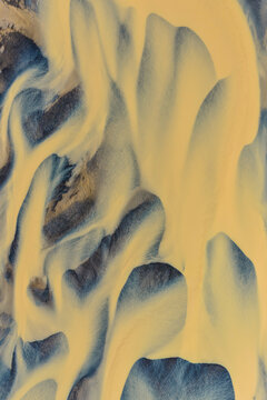 Aerial view of the braided glacial river patterns flowing from Drangajokull, with intricate sediment channels and dark volcanic terrain in Isafjordur, Isafjardarbaer, Iceland.