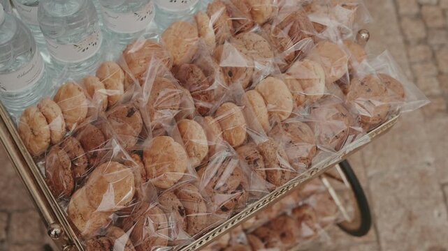 Individually wrapped cookies in cellophane bags beside water bottles on serving tray