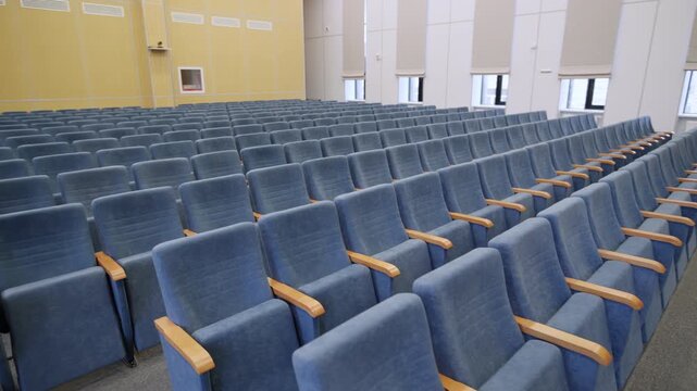 Assembly hall features upholstered velvet theater seating along light wall. Lecture room design provides cozy atmosphere for public events