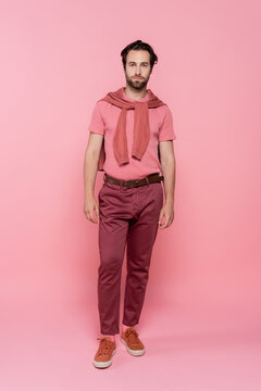 Handsome stylish man showcases summer fashion with a confident smile against a pink backdrop