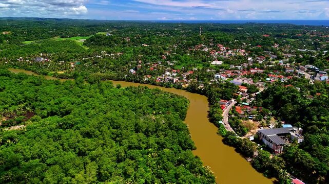Nilwala River curves beside dense riverside forest and the town of Matara under bright midday skies, useful as a regional establishing shot.