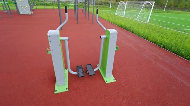 Elliptical trainer stands on rubber surface near football field. Sports equipment provides excellent opportunities for cardio workouts