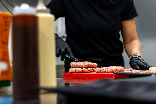 Chef preparing raw burger patties in a professional kitchen for a gourmet small business