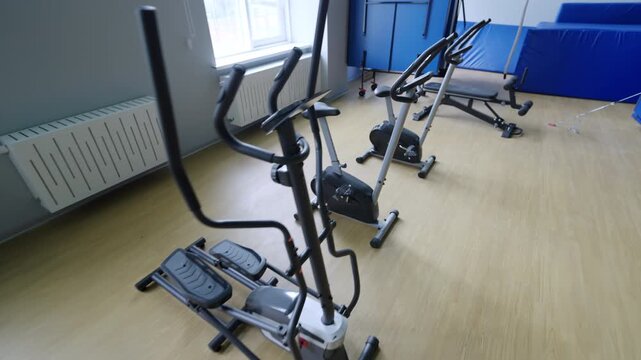 Elliptical trainers stands along windows in indoor gym. Cardio equipment provides opportunities for endurance training and active lifestyle