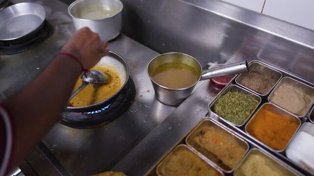 Chef Stirring Yellow Curry Sauce in Frying Pan on Gas Stove