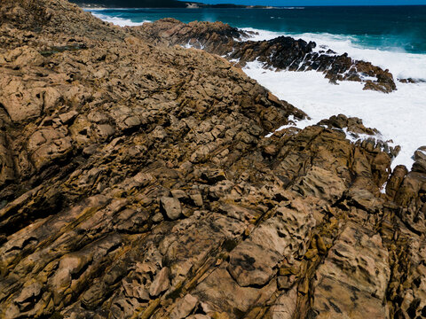 Aerial view of the rugged rock formations at Injidup Natural Spa, with crashing turquoise waves and white sea foam along the coastline in Yallingup, Western Australia, Australia.