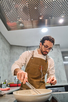 Chef cooking meal in modern home kitchen wearing apron