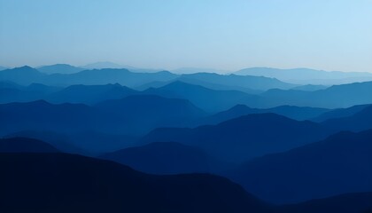 Fototapeta premium Serene mountain range landscape under clear blue sky with misty hills