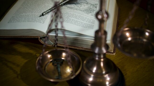A detailed close-up of a brass scale of justice with a sword displayed against a blurred background of law books in warm light.