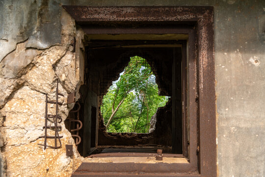 View of the weathered concrete walls and jagged opening of the historic North Field Base, revealing lush green foliage in Northern Tinian, Tinian, Northern Mariana Islands.