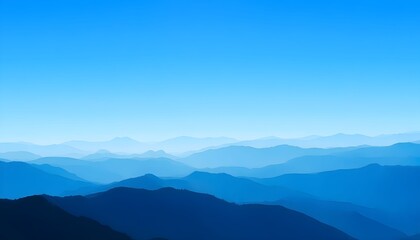 Fototapeta premium A serene mountain range landscape with hazy blue mountains under a clear blue sky.