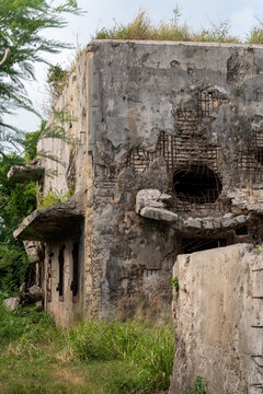 View of the historic North Field Base ruins featuring weathered concrete walls, exposed rebar, and overgrown vegetation in Northern Tinian, Tinian, Northern Mariana Islands.