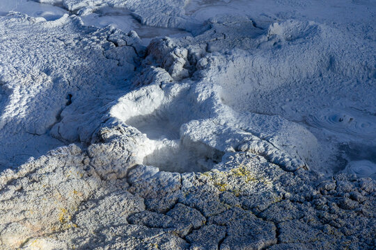 View of Geisers Sol de la Manana featuring bubbling mud pools, steaming vents, and cracked volcanic earth in Sur Lipez, Potosi Department, Bolivia.