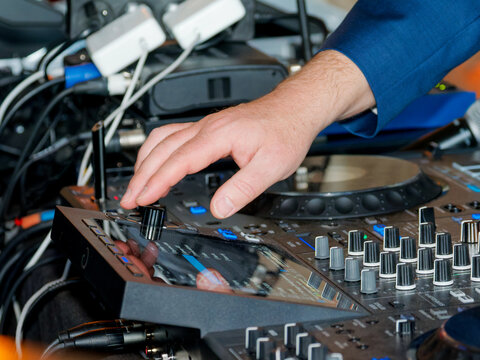 Main d&rsquo;un DJ r&eacute;glant une console de mixage lors d&rsquo;une soir&eacute;e priv&eacute;e ou d&rsquo;un &eacute;v&eacute;nement festif