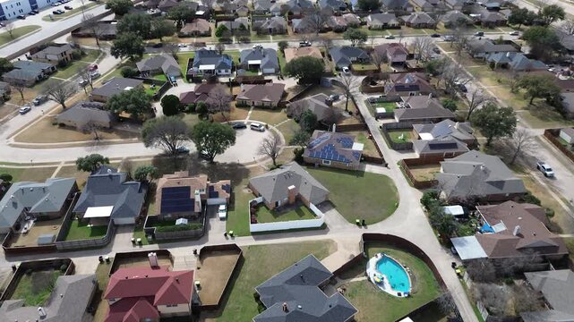 Plano community cul-de-sacs reveal suburban living arrangements near the busy North Central Expressway corridor. Varied roof pitches and backyard pools overlook sprawling residential lots, Texas