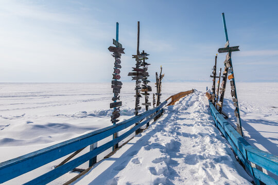 View of Goryachiye Istochniki Khakusy with wooden signposts on a snow-covered pier leading onto the frozen surface of Lake Baikal in Severobaykalskiy Rayon, Respublika Buryatiya, Russia.