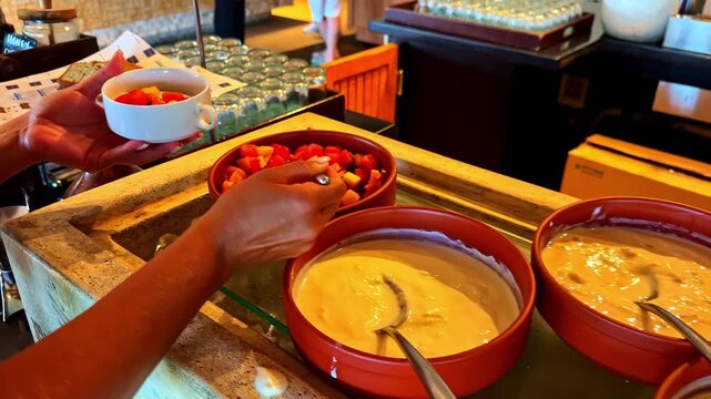 Guest serving fresh fruit and yogurt parfaits from a breakfast buffet counter