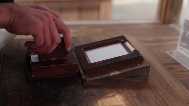 Hand pressing traditional wooden hanko stamp onto ink pad on wooden surface at Katsuoji Temple Osaka Japan