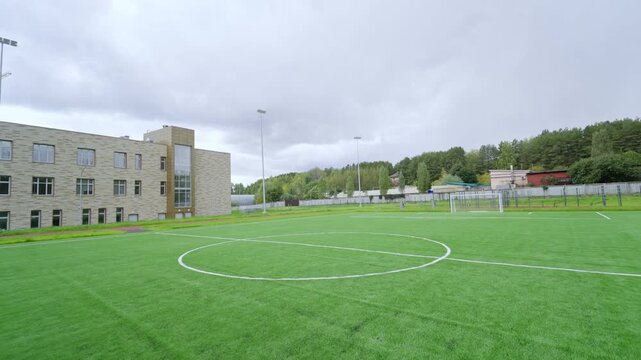 Spacious outdoor stadium offers professional turf for student activities. Lighting poles and overcast sky create clean urban playground