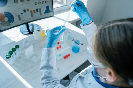 A researcher in a white lab coat performs scientific experiments with liquid samples in a bright laboratory. Digital data visualizations and scientific tools enhance the innovative workspace