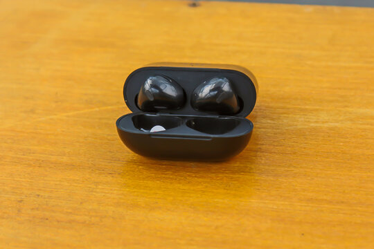 Wireless Black Earbuds on Wooden Surface with Minimal Background