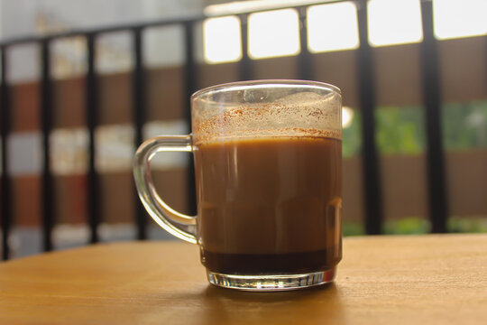 Cup of Hot Milk Coffee in Glass Mug on Wooden Table with Copy Space