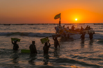 Fishing boat with Mauritanian flag on the coastline of Nouakchott beach, Mauritania, with fishermen bringing fish at the local market.  © Artaxerxes