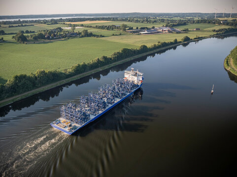 Aerial view of heavy lift cargo vessel transporting wind turbine component in storage racks on Kiel Canal Germany.