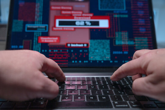 Hacker types on a laptop keyboard and starts an illegal download of sensitive data, computer crime. Data breach, computer virus, firewall, privacy, netowrk security, data protection.