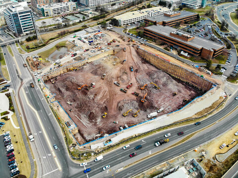 Reston, Virginia, United States - 12 March 2019: Aerial view of a large construction site with heavy machinery, excavators, and earthmoving equipment near office buildings.