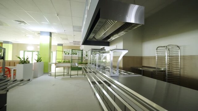 Canteen food distribution zone displays metallic equipment and counter. Catering interior design promotes efficient student service