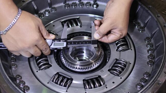 ​Close-up of a mechanic using a digital vernier caliper to measure the inner diameter of an automatic transmission torque converter hub in a workshop.