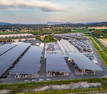 Livron-sur-Drome, France - 20 June 2026: Aerial view of a vehicle salvage yard with rows of damaged and end-of-life cars parked under large solar panel canopies.