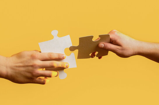 Connecting jigsaw puzzle. Two hands trying to connect couple puzzle. Business solutions, success and strategy concept