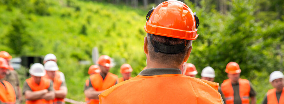 Builders, hardhats. Group of builders in hard hats and reflective vests. Engineer in the act of note record for inspect the construction site