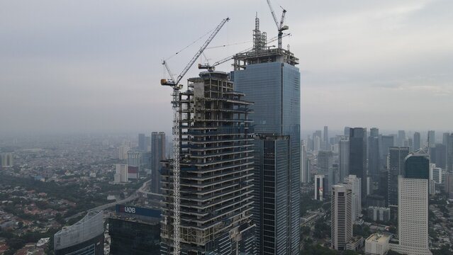 Kecamatan Menteng, Daerah Khusus Ibukota, Indonesia - 03 December 2021: Aerial view of a skyscraper under construction with tower cranes and steel framework rising above the city skyline.