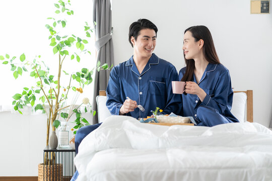 寝室で朝食を食べるミドルの夫婦