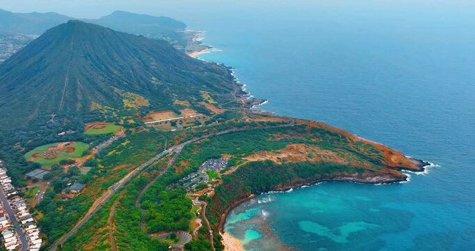 Koko crater and Hanauma bay coastline from elevated perspective, Oahu, Hawaii. Drone view of volcanic ridge above turquoise protected cove, winding road, sandy beach and deep blue Pacific ocean.