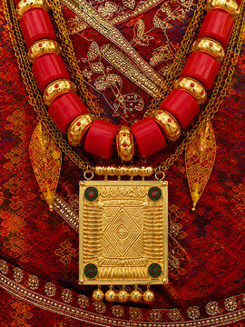 Traditional South Asian Gold Pendant Necklace with Red Coral Beads on Red Fabric