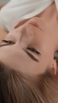 A peaceful young woman rests with her eyes closed, her face illuminated by gentle daylight. The image evokes calmness, self care, and modern beauty trends in a minimalist style