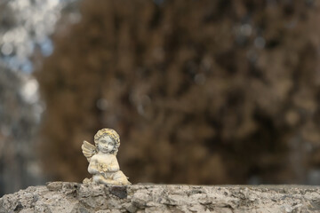 Obraz premium Beautiful little angel baby figurine on stone close up, abstract nature background. concept of faith, Christianity, memory, religion. design card for condolence, mourning card or obituary. copy space