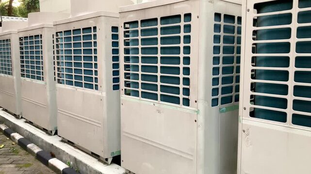 row of large industrial outdoor air conditioning condenser units next to a building
