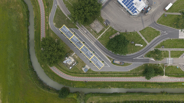 Bunnik, Utrecht, Netherlands - 16 June 2026: Aerial view of a solar panel installation covering a parking area, adjacent to a canal, road, and green fields.