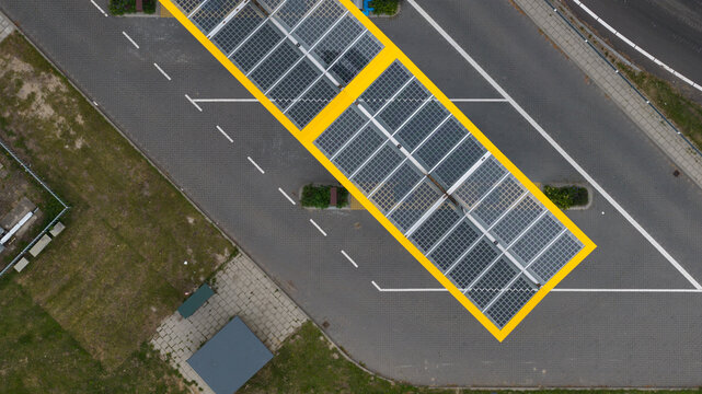 Bunnik, Utrecht, Netherlands - 16 June 2026: Aerial view of a solar panel canopy covering a parking lot with white painted parking lines and asphalt surface.