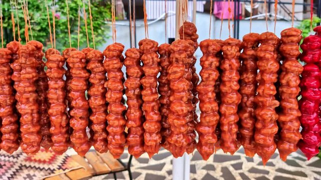 Colorful churchkhela sweets displayed on strings at a vibrant outdoor market stall