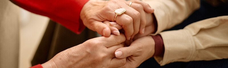 Fototapeta premium Website header shot of adult women holding hands, showing comfort, empathy, support during difficult conversation, close up. Ideal for counseling, caregiving, mental health, trust messaging