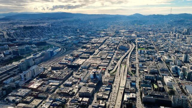 Freeway interchange and residential neighborhood near Potrero Hill, San Francisco. Elevated drone view over multilane highway junction, industrial warehouse district and city grid.