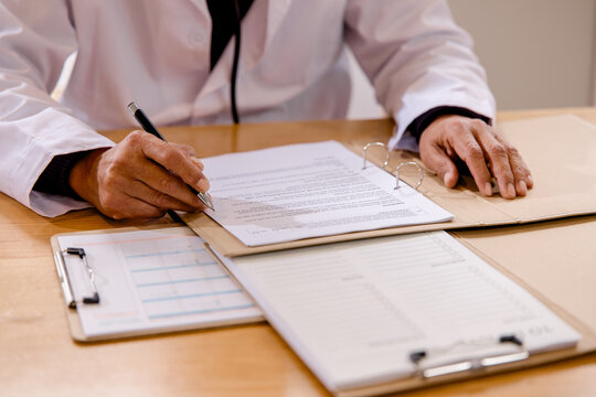 Senior doctor reviewing signing medical documents in a healthcare office. completing patient records, clinical paperwork, administration, diagnosis healthcare management.
