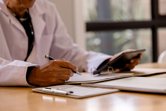 reviewing patient records and using a digital tablet in a healthcare office. doctor completing medical documentation, clinical administration, and modern healthcare management.