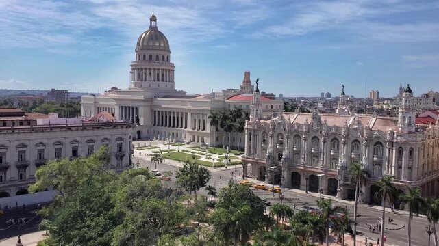View of the neoclassical El Capitolio building with its iconic dome, surrounded by historic architecture, palm trees, and city streets in Havana, Havana, Cuba.